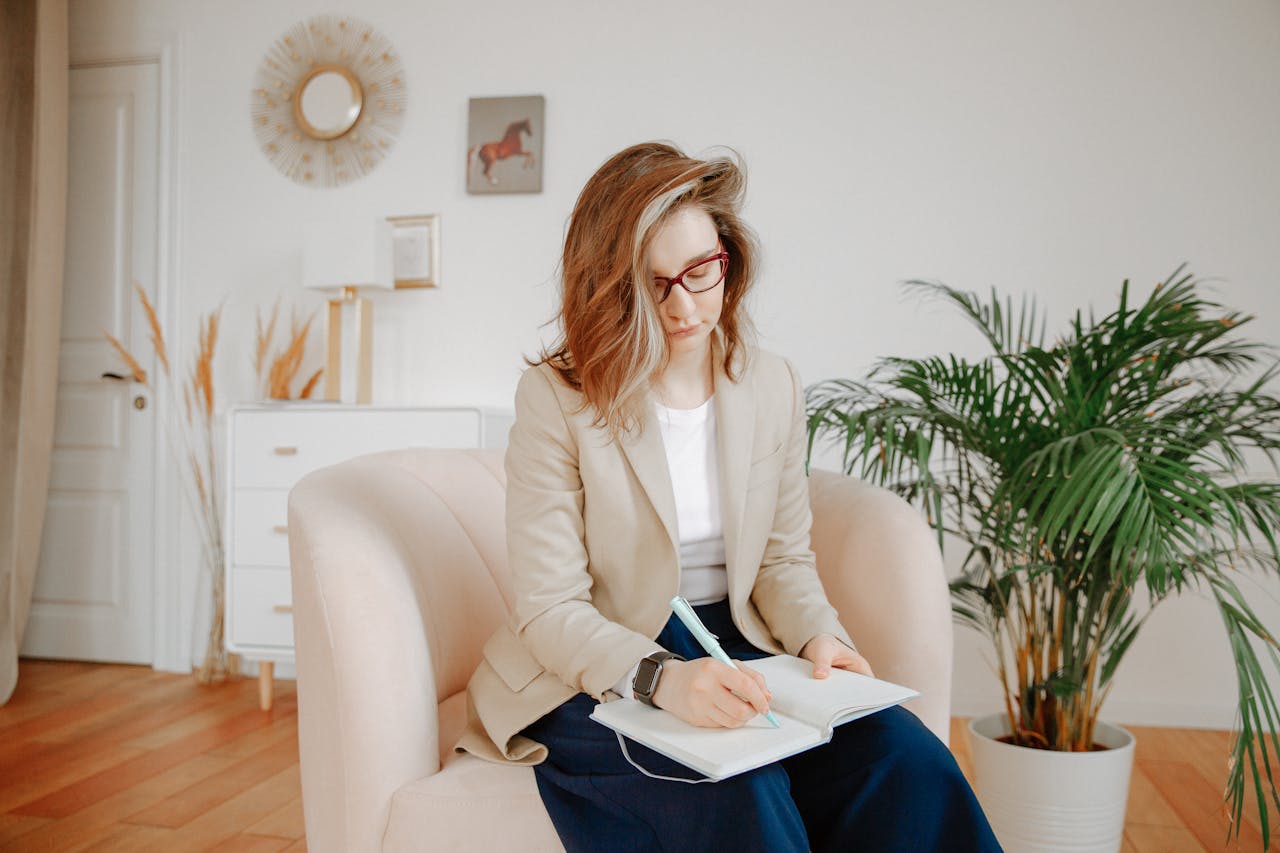 our-story A female therapist taking notes during a session in a stylish office setting.